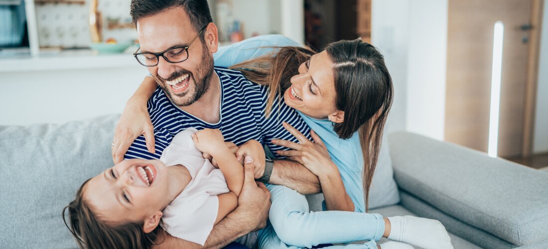 young family having fun on the couch in the home they own.