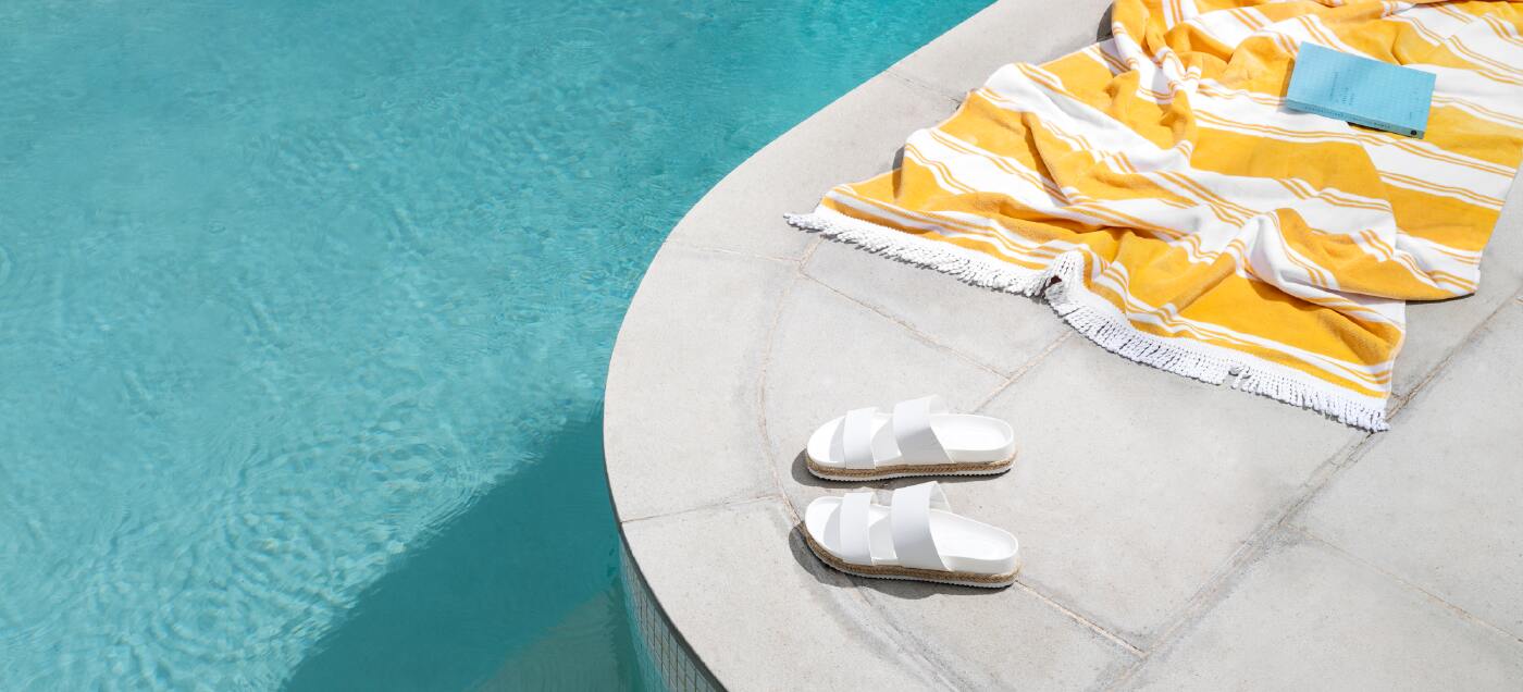 a swimming towel draped by a crisp blue pool at a holiday home you just invested in.